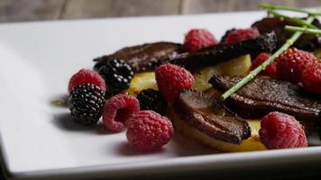 foto rotativa de um delicioso prato de bacon de pato defumado com abacaxi grelhado, framboesas, amoras e mel - comida 100