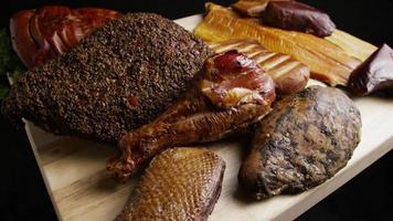 Rotating shot of a variety of delicious, premium smoked meats on a wooden cutting board - FOOD 056 video