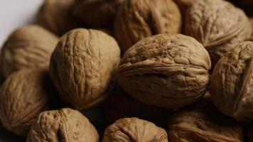 Toma cinematográfica giratoria de nueces con cáscara sobre una superficie blanca - nueces 073 video