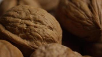 Cinematic, rotating shot of walnuts in their shells on a white surface - WALNUTS 077 video