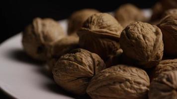 Cinematic, rotating shot of walnuts in their shells on a white surface - WALNUTS 086 video