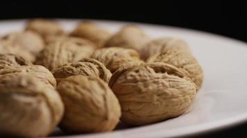 Cinematic, rotating shot of walnuts in their shells on a white surface - WALNUTS 031 video