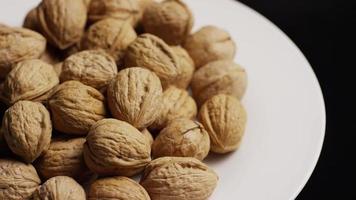 Cinematic, rotating shot of walnuts in their shells on a white surface - WALNUTS 069 video