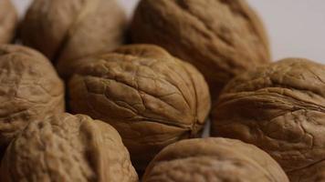 Cinematic, rotating shot of walnuts in their shells on a white surface - WALNUTS 017 video