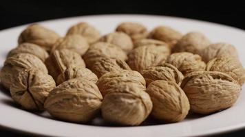 Cinematic, rotating shot of walnuts in their shells on a white surface - WALNUTS 027 video