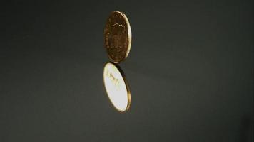 goldene Münze, die sich in Ultra-Zeitlupe (1.500 fps) auf einer reflektierenden Oberfläche dreht - Geldmünzen-Phantom 002 video