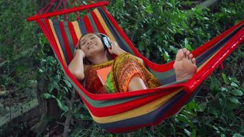 Young woman listening to music on a hammock.