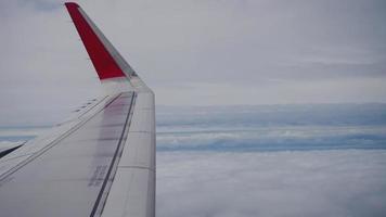 Wing of an airplane flying above the clouds from window plane view video