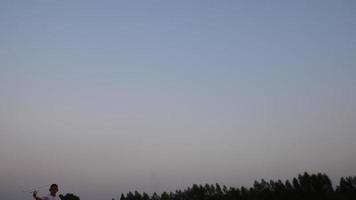 Boy running in a field with a toy wooden airplane in his hands at sunset video