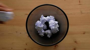 Hand Throw crumpled paper into trash with wood table background video