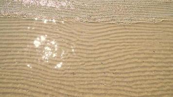 mjuk våg av havet på sandstranden. sommar textur bakgrund video