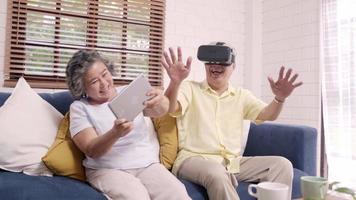 Pareja de ancianos asiáticos con tableta y simulador de realidad virtual. video