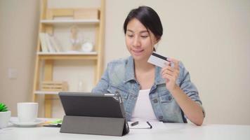 mujer asiática con tableta para comprar en línea con tarjeta de crédito. video