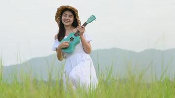 Mujer feliz en vestido blanco tocando la guitarra ukelele video