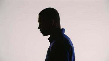 Silhouette of a young black man tilting his head left-down and then right-down video