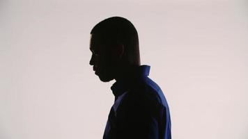 Silhouette of a young black man meditating and tilting his head down then up and finally down video