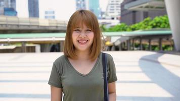 jovem atraente sorridente mulher asiática retrato ao ar livre na série de pessoas reais da cidade. video