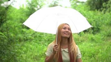 mujer caminando mano sosteniendo paraguas blanco en el parque