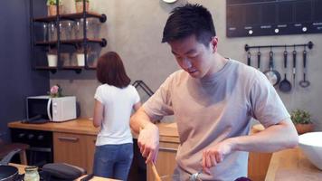 asiatisk man förbereder salladmat i köket. vackra lyckliga asiatiska par lagar mat i köket. video