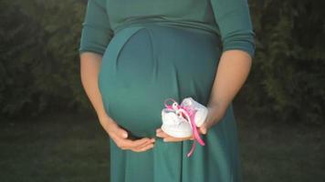 schwangere Frau, die weiße Kinderschuhe hält video