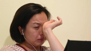 Portrait of crying woman with earphone and smartphone video