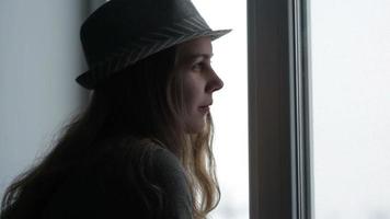 ung kvinna som tittar ut genom fönstret