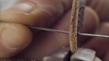 le maître du cuir fait clignoter le bracelet avec du fil noir. macro 4k video