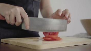 kock som hugger tomat på skärbräda i köket. video