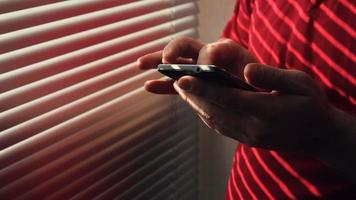 Man Stands Near Window In Hotel Room And Uses Smartphone