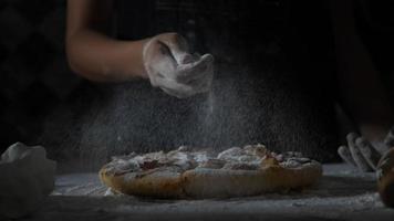 Cámara lenta de las manos de una mujer tamizando la harina sobre una pizza