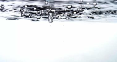  Five groups of drops falling and splashing on a water container creating waves and little bubbles in 4K video