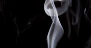 weiße Textur des tanzenden Rauches, der die Szene auf dunklem Hintergrund in 4k füllt
