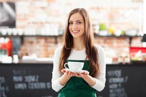 Waitress holding cup of coffee in cafe photo