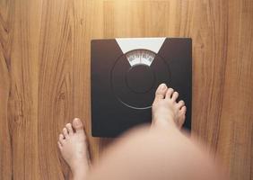 Woman's feet standing on weight scale photo