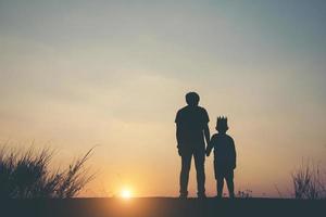 Silhouette of father and son standing together photo