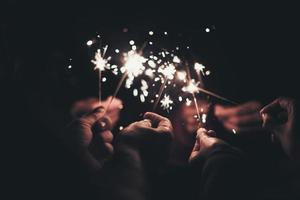 Group of people holding sparklers at night photo