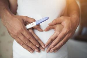 Pregnant woman and her husband with hands showing heart shape photo