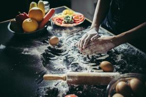 Woman kneads dough for pizza photo