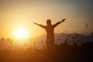 Silhouette of a woman praying over a beautiful sky background photo