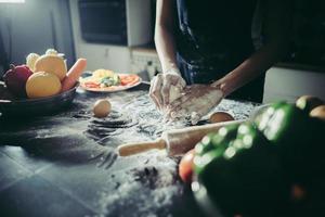 Woman kneads dough for pizza photo