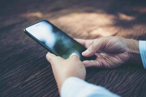 Person holding smart phone at a table photo