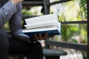 Young man reading books in home garden with nature photo