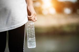 Colocar joven mujer sosteniendo una botella de agua después de correr foto