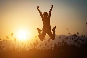 Silhouette of a woman jumping over a beautiful sky background photo