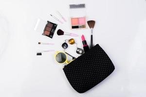 Vista superior de una bolsa de maquillaje con productos de belleza. foto