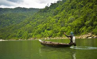 Men rowing a boat near green hill during daytime photo