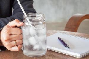 Person holding a glass of water on a table photo