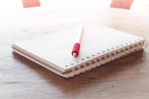 Notebook and a red pencil in sunlight photo