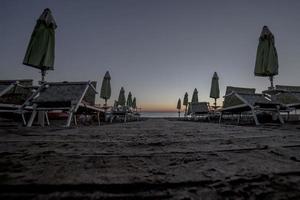 Tumbonas con sombrillas en la playa al atardecer foto