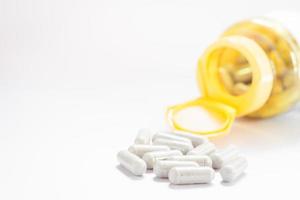 Pills and a yellow bottle on a white background with copy space photo